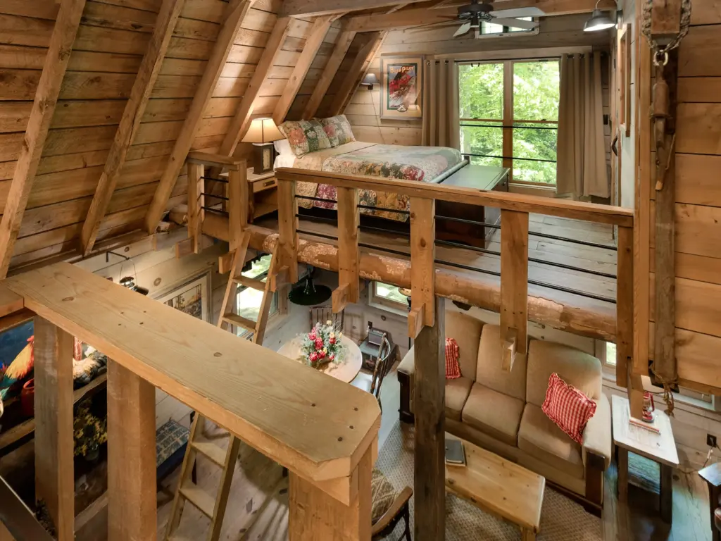 Rustic wood cabin interior featuring a cozy living area and a sturdy wooden ladder leading to a loft bedroom.