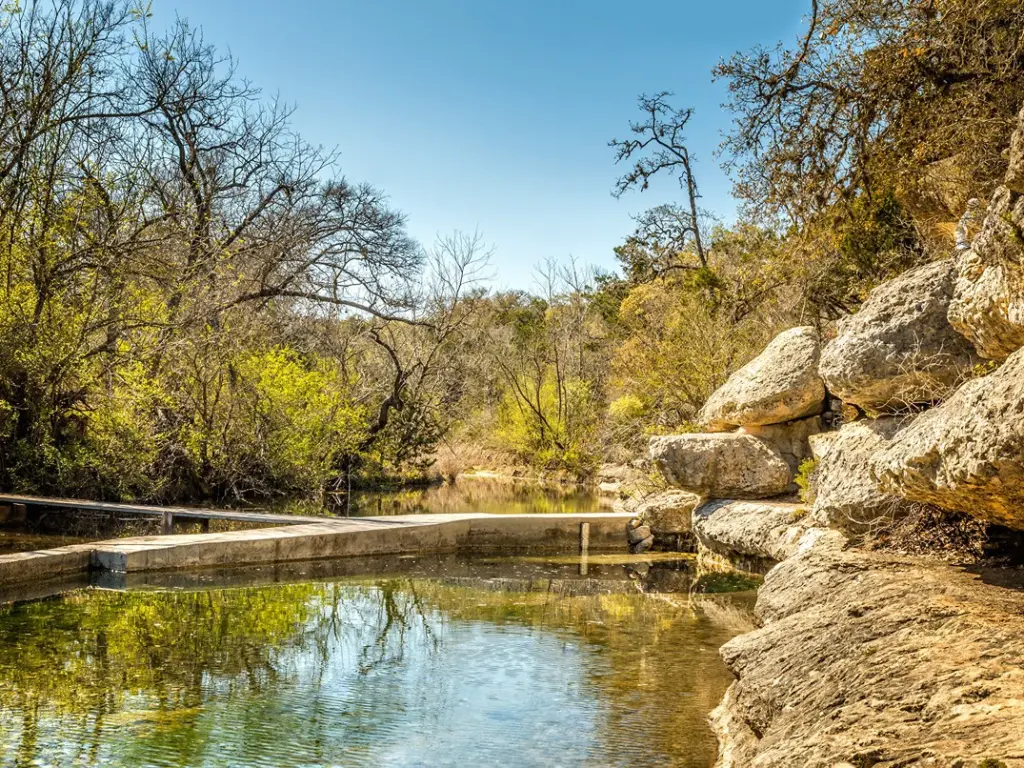Clear spring surrounded by rocky cliffs at Jacob's Well, a popular nature spot near Wimberley TX Cabins