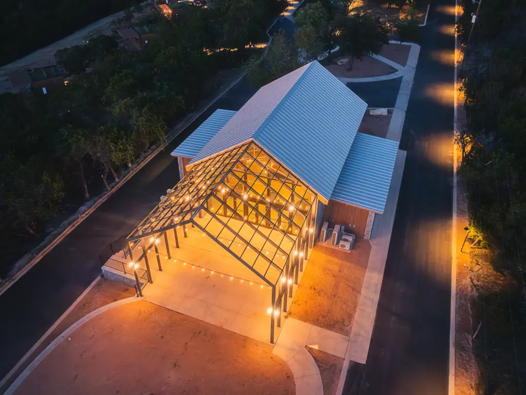 Illuminated greenhouse event space at Onera resort viewed from above at night.