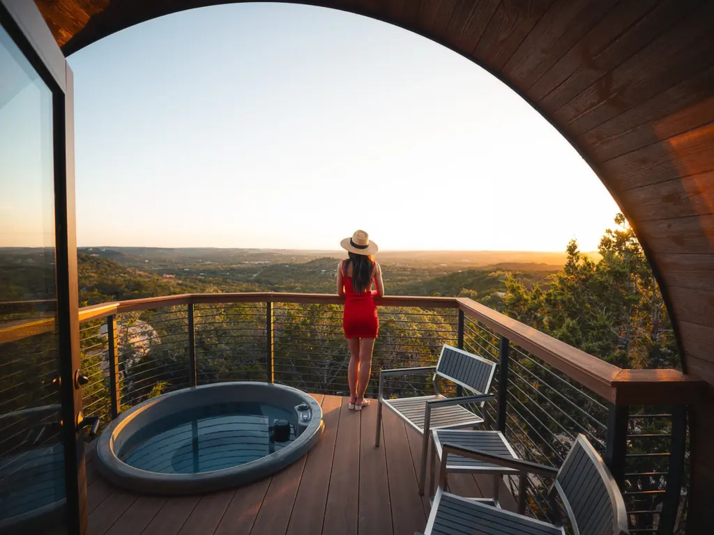 Woman in a red dress enjoying a valley sunset from a curved balcony with a private hot tub.