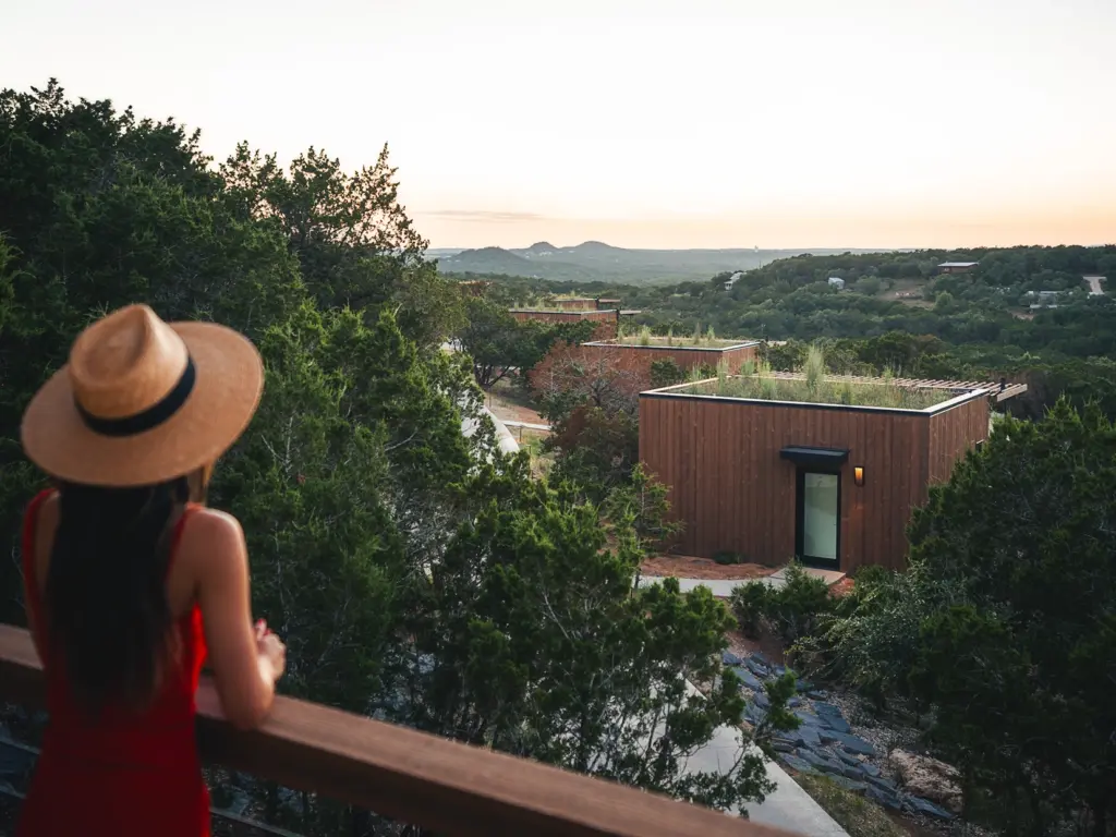 Woman in a sun hat overlooking modern, eco-friendly cabins nestled in the Texas hills at Onera.