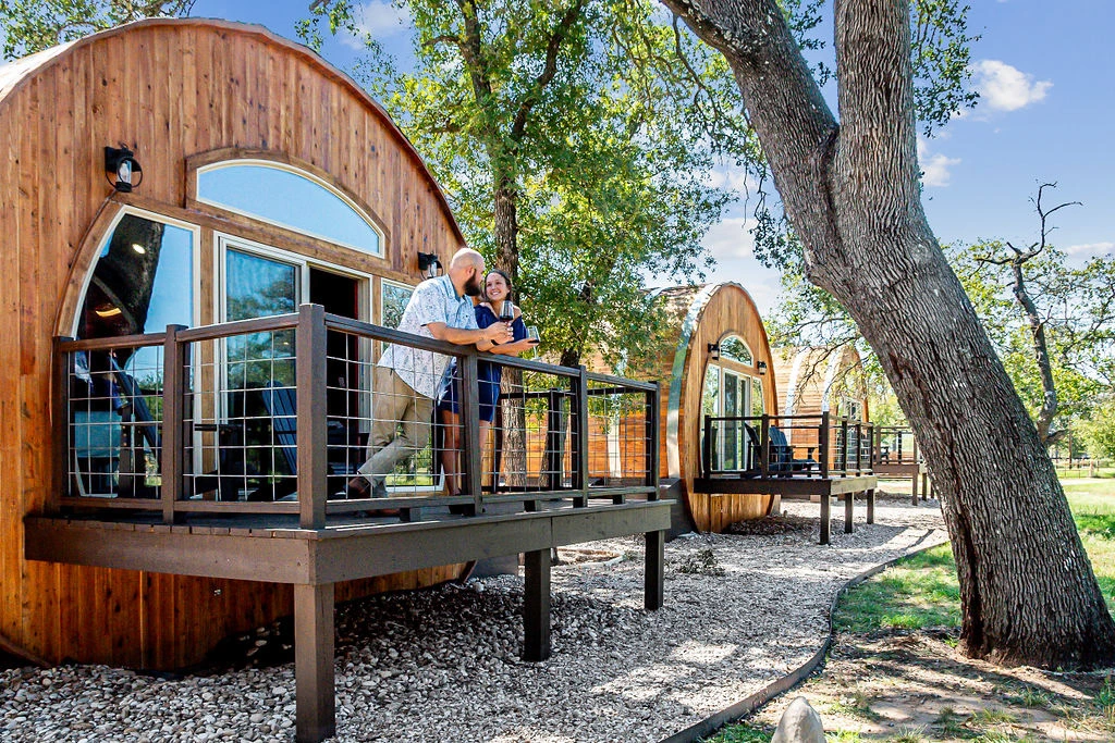 Couple enjoying wine on the deck of unique wine barrel-shaped Wimberley TX Cabins.