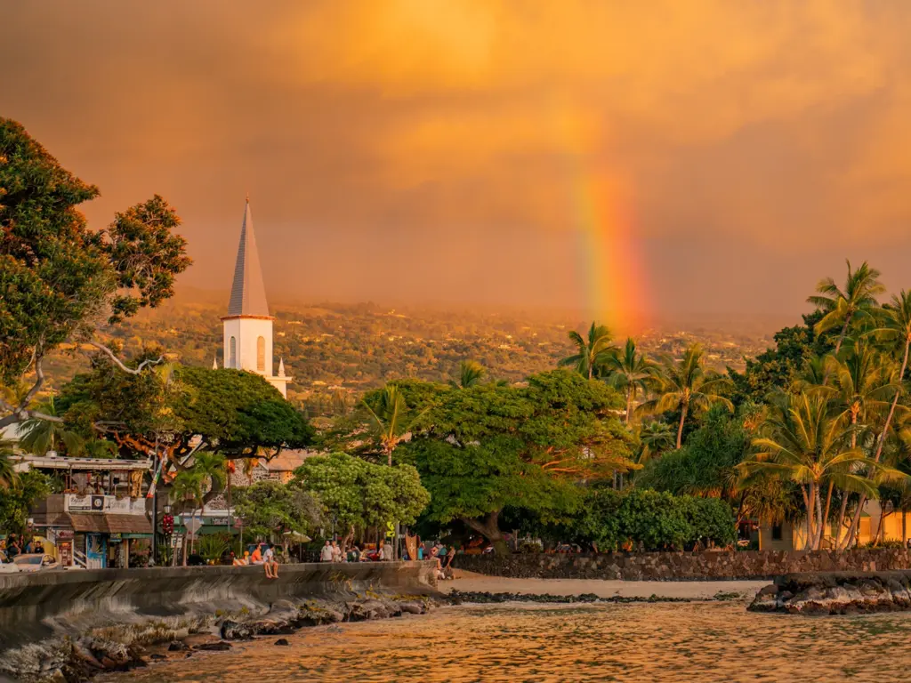 Golden hour rainbow over Mokuaikaua Church and the coast near design hotels kailua kona.