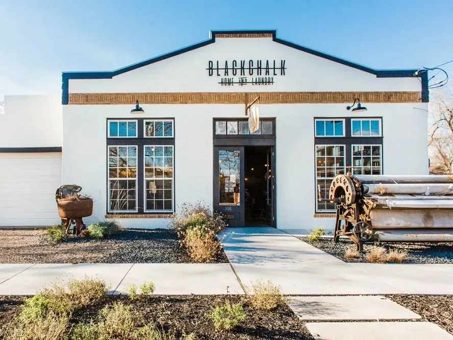 Blackchalk Home and Laundry storefront with white facade, dark trim, large windows, and vintage industrial decor outside.