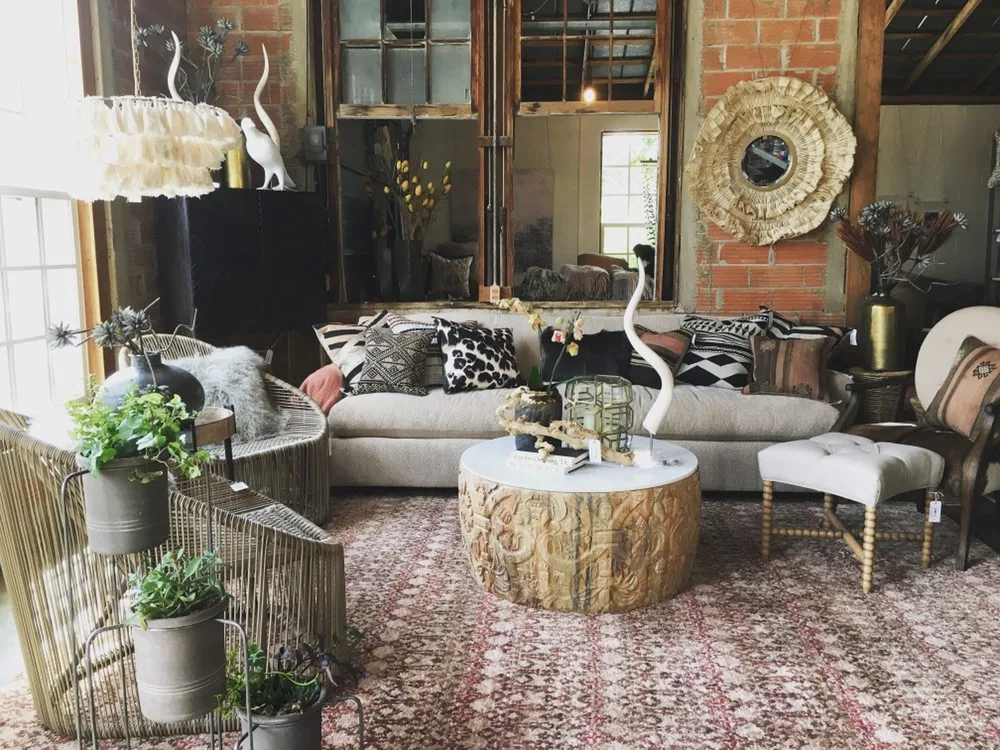 Carved wood coffee table and patterned pillows styled in a boho living room at shops in Fredericksburg TX.