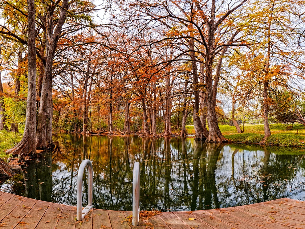 Wooden dock at Blue Hole Regional Park reflecting autumn trees, offering views for those planning where to travel in august.