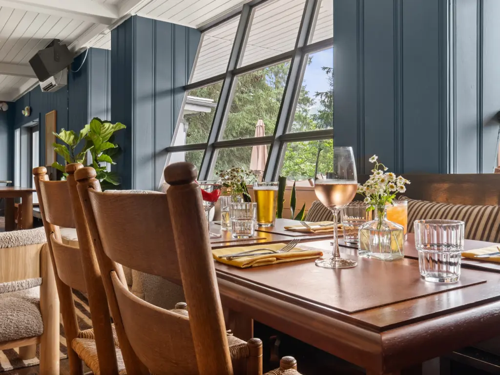 Table set with drinks by a large slanted window overlooking the trees at Callicoon Hills.