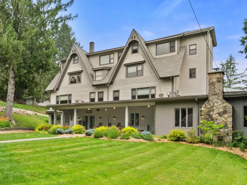 Large gray hotel building with peaked roofs at Callicoon Hills, a charming stay when choosing where to travel in august.