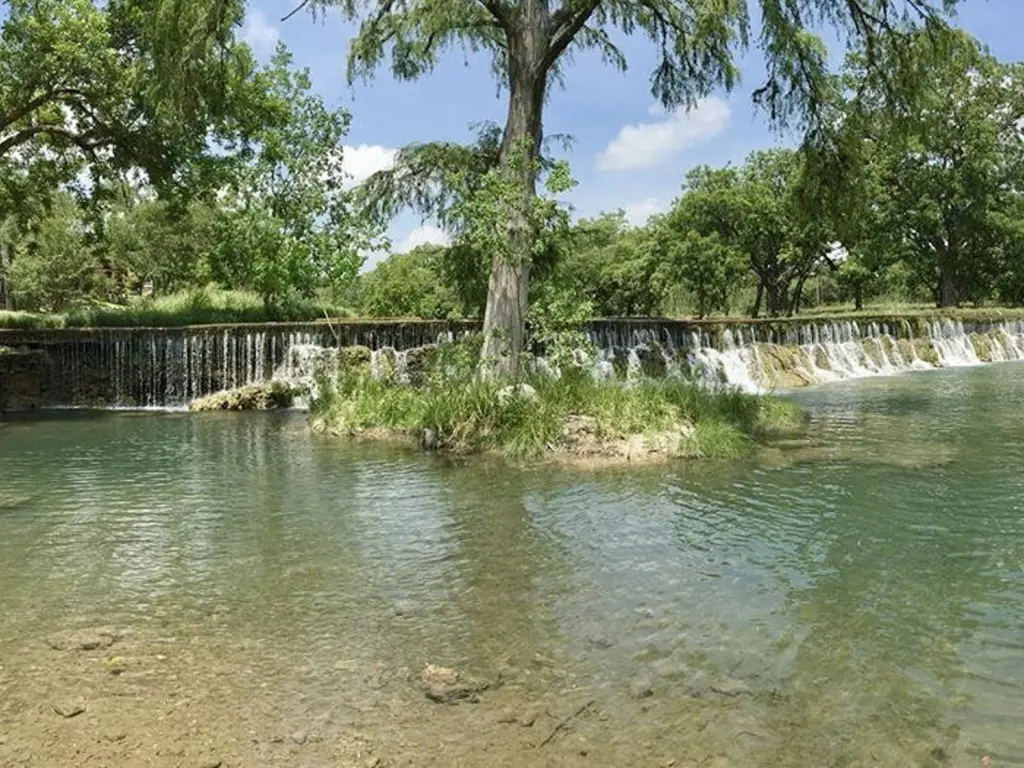 Wide waterfall cascading into a pool surrounded by trees, a perfect spot when deciding where to travel in august.