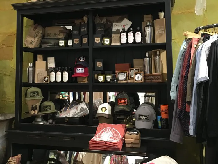 Black display shelving unit stocked with hats, candles, bottles, and gifts at shops in Fredericksburg TX.