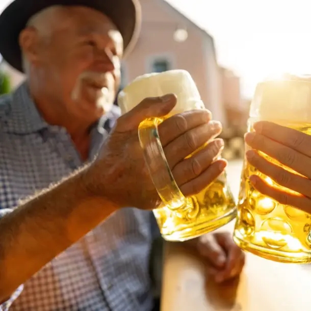 Two people clink large glass mugs of beer together while celebrating at the Fredericksburg Oktoberfest.