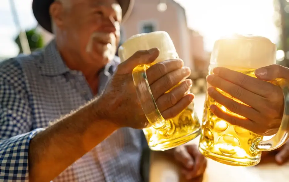 Two people clink large glass mugs of beer together while celebrating at the Fredericksburg Oktoberfest.