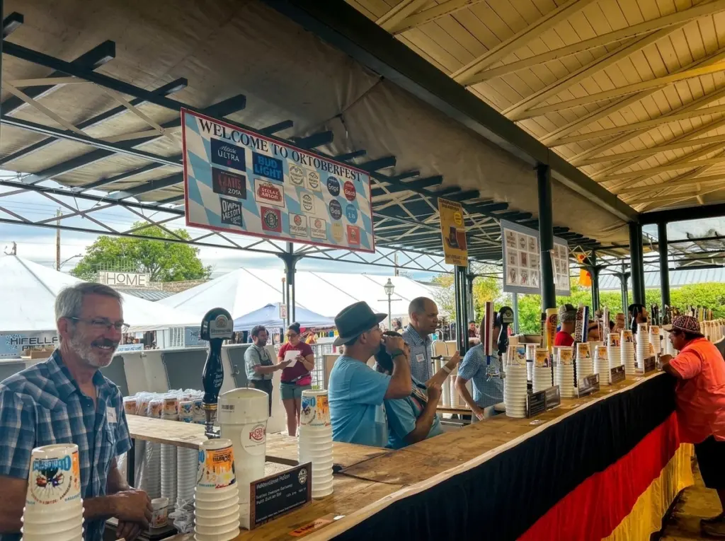 Attendees order drinks at a long wooden bar with beer taps at the Fredericksburg Oktoberfest.