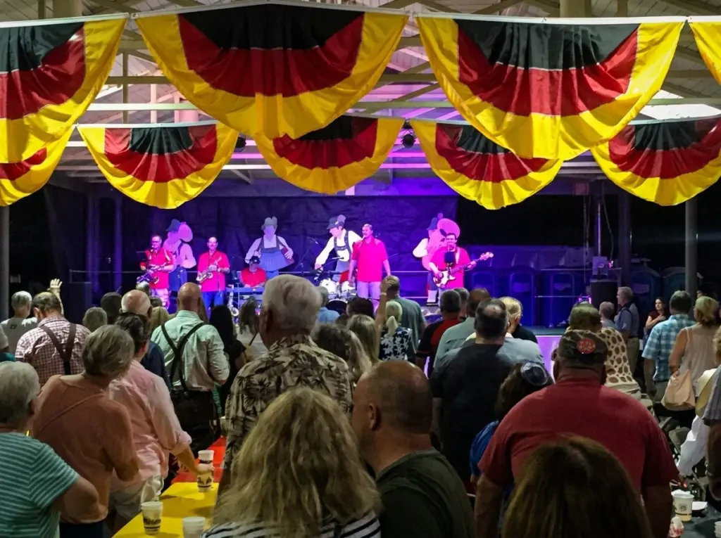 A band performs for a crowd under a pavilion decorated with German flags at the Fredericksburg Oktoberfest.