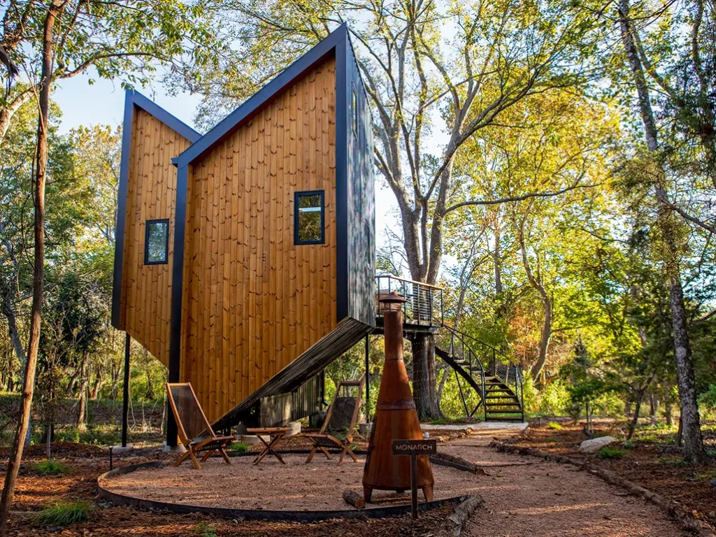 The exterior of the modern, angular Monarch treehouse cabin in the woods at Onera Fredericksburg.