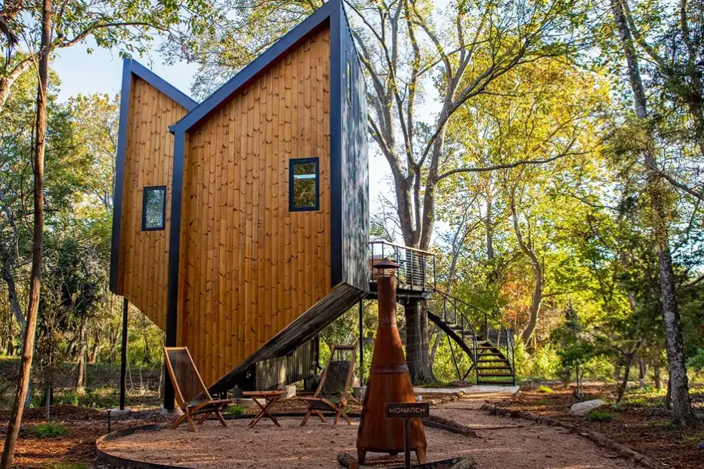 The exterior of the modern, angular Monarch treehouse cabin in the woods at Onera Fredericksburg.