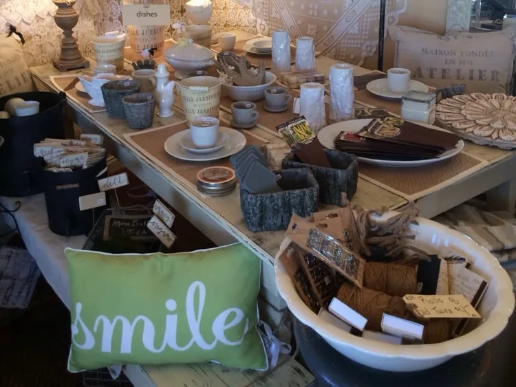 Rustic dishes, mugs, planters, and a smile pillow displayed at a home décor shop in Fredericksburg, TX