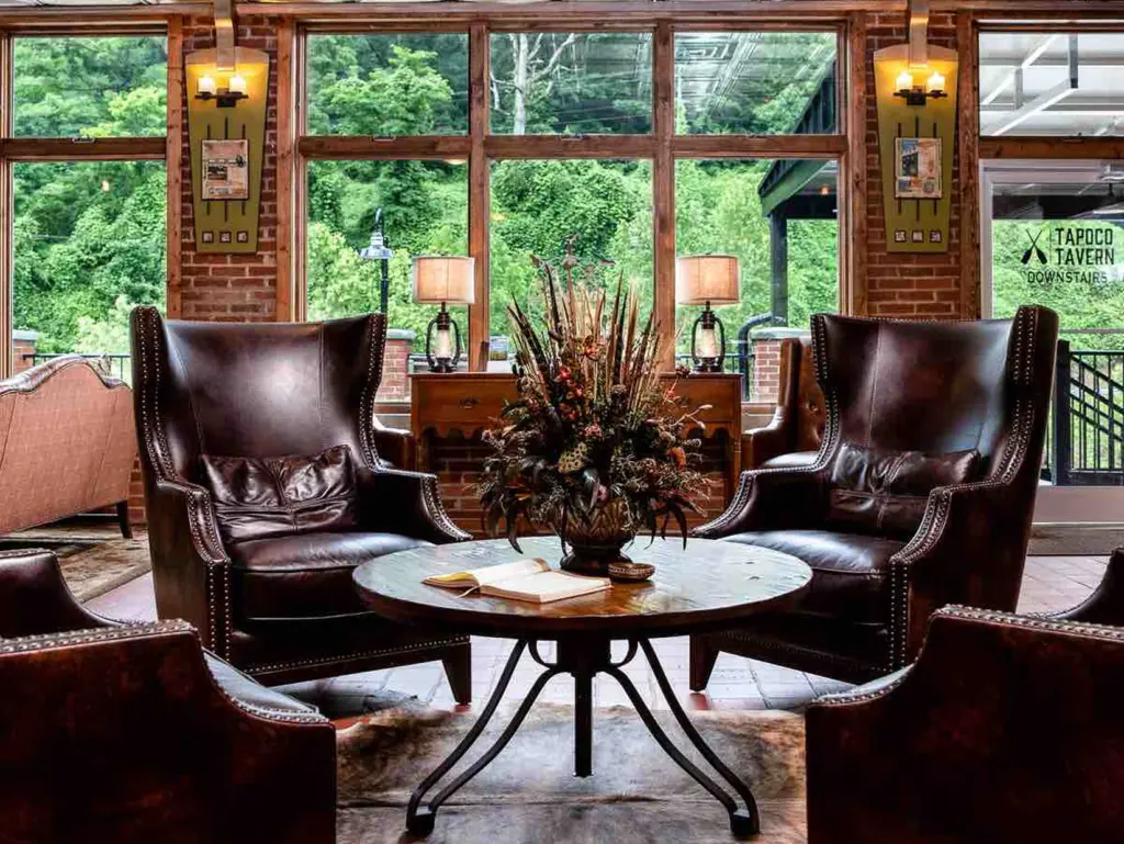 Leather wingback chairs around a wooden table at Tapoco Tavern, a relaxing spot for where to travel in august.