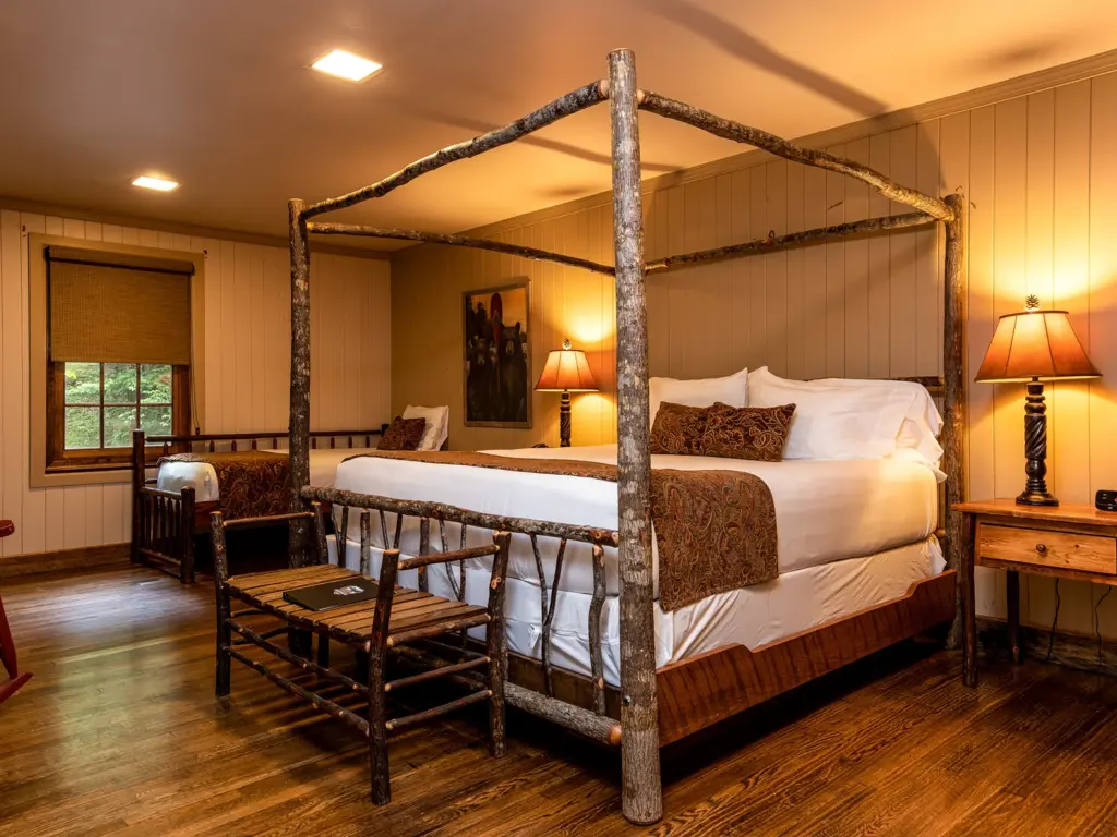 Rustic hotel room featuring a wood canopy bed and warm lighting, a cozy option for where to travel in august.