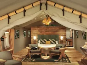 King bed, wood-paneled walls, and string lights inside a glamping tent typical of design-forward nature retreats.