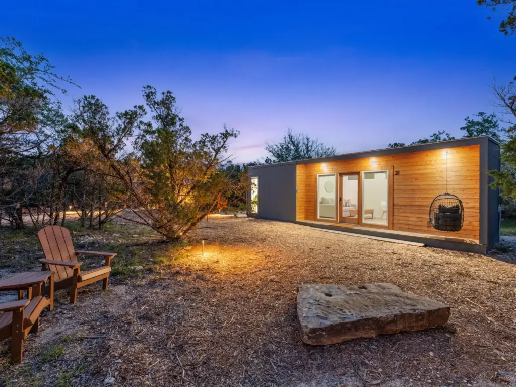 Modern container home with cedar wood siding and sliding glass doors glowing at dusk, surrounded by native trees and gravel.
nature immersive corporate offsites