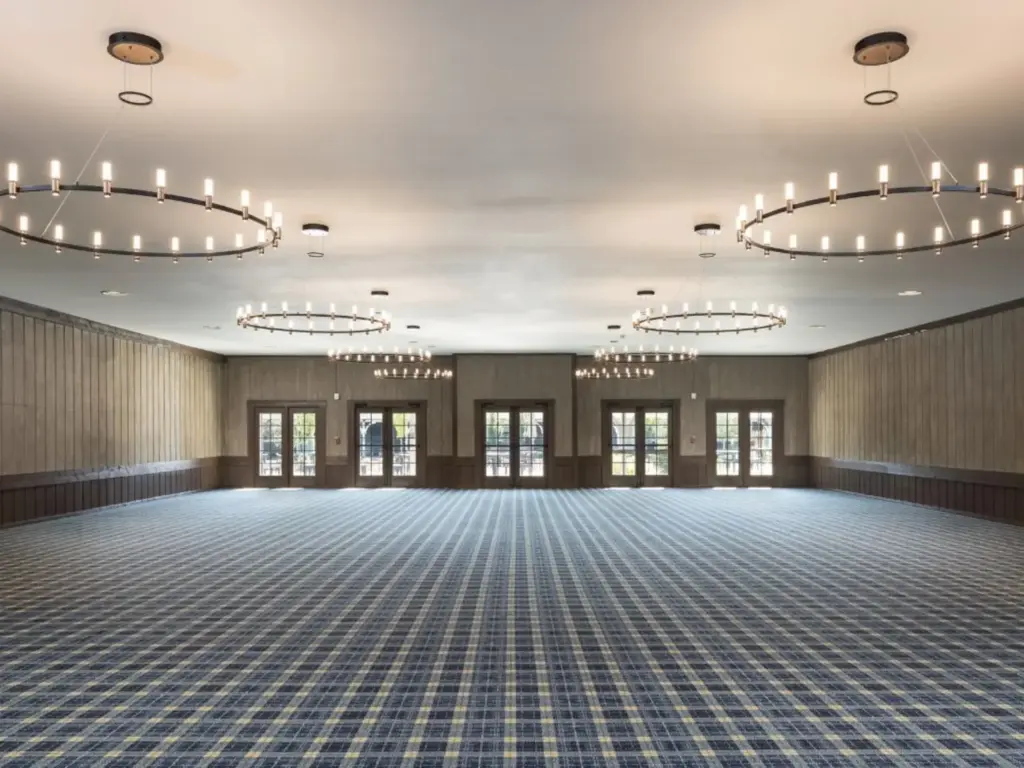 Large empty ballroom with plaid carpet, wood-paneled walls, French doors, and circular chandeliers.
nature immersive corporate offsites