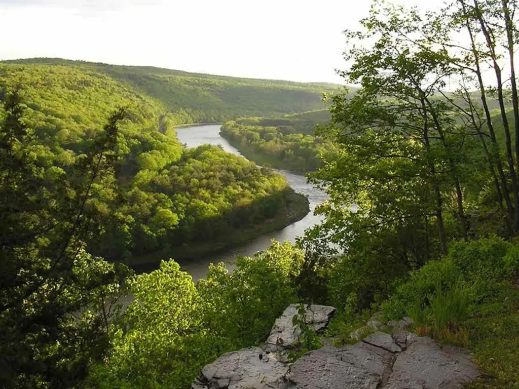 Scenic rocky overlook viewing a wide river winding through a green valley, perfect for where to travel in august.
