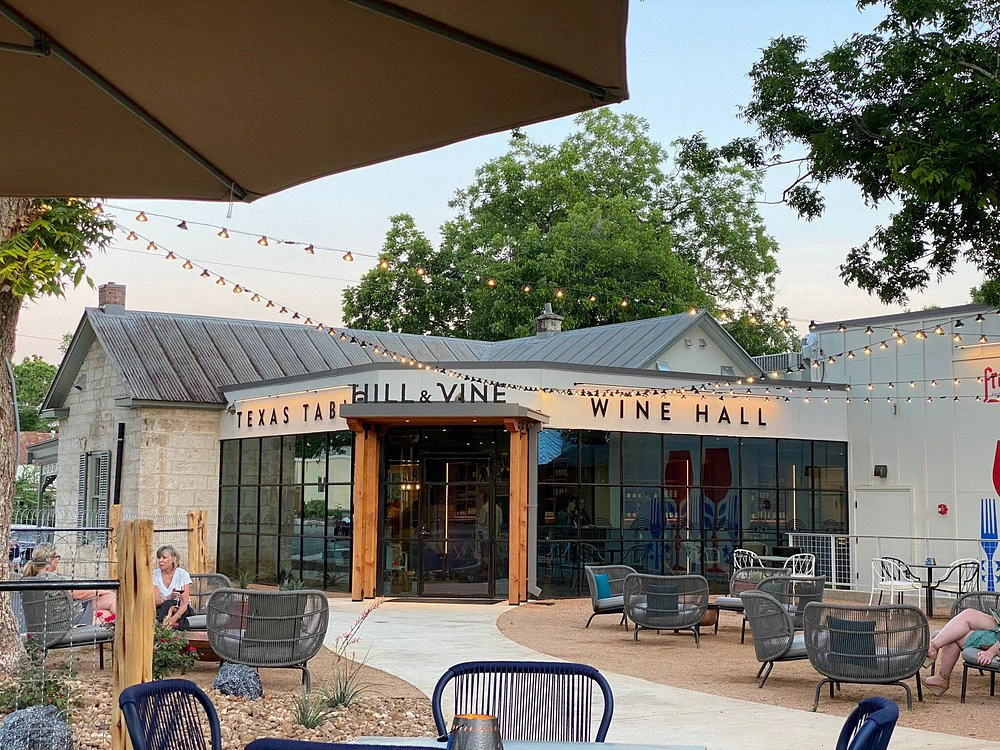 Outdoor patio at Hill & Vine, one of the best restaurants in fredericksburg tx, featuring string lights and seating.