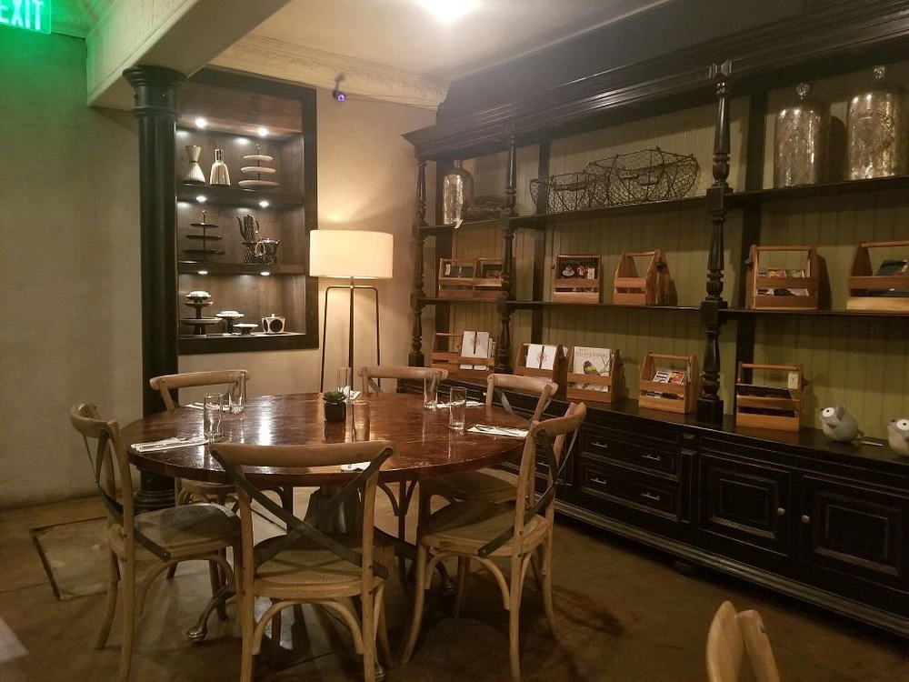 A rustic wooden dining table and chairs set up inside the dimly lit dining room of Vaudeville.
