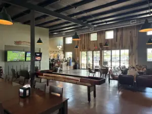 Rustic interior at one of the breweries in Fredericksburg Texas, with shuffleboard, pendant lights, and wood accent walls.